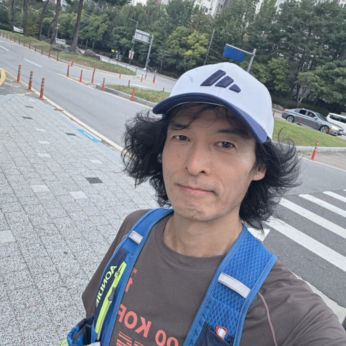 흰 모자와 러닝 조끼를 입고 길가에서 셀카를 찍은 러너